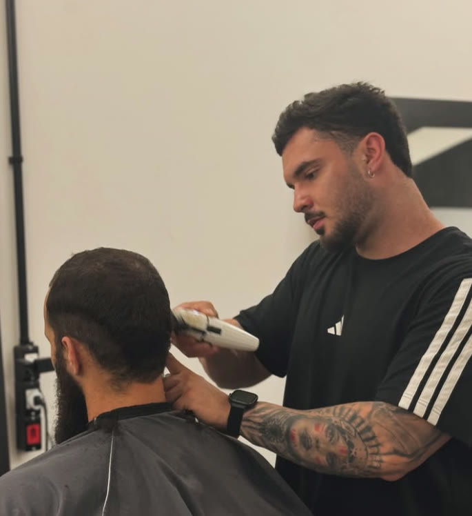 Paulo Dacampo passando a máquina na nuca de um cliente